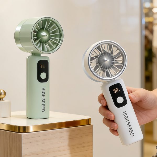 Green digital display fan standing on a tabletop beside White fan held in a hand