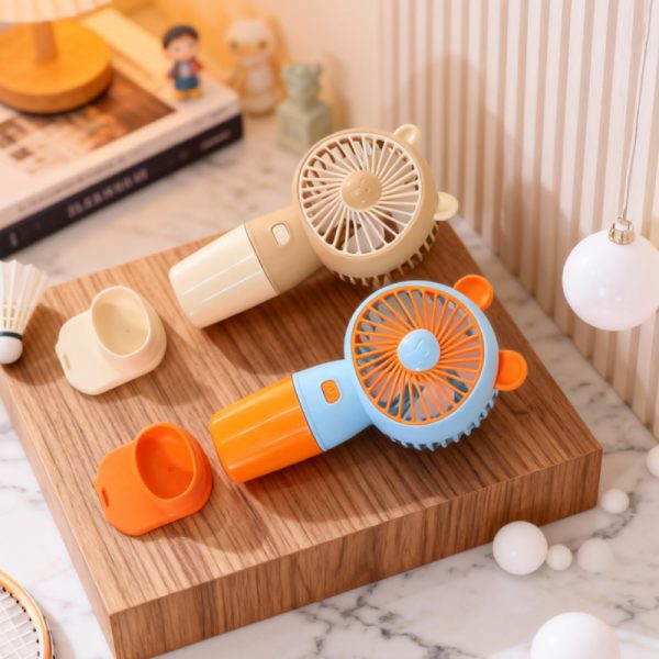 Apricot and orange bear-ear handheld fans beside detached desktop bases