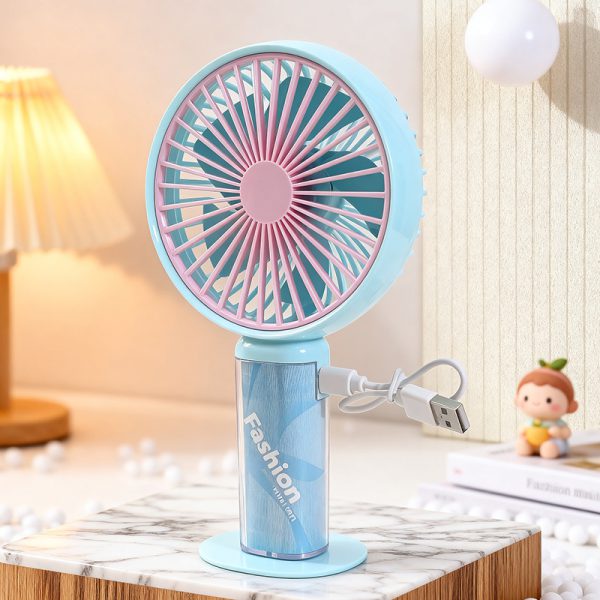 Azure Blue transparent-handle handheld fan on a desk with a USB charging cable connected