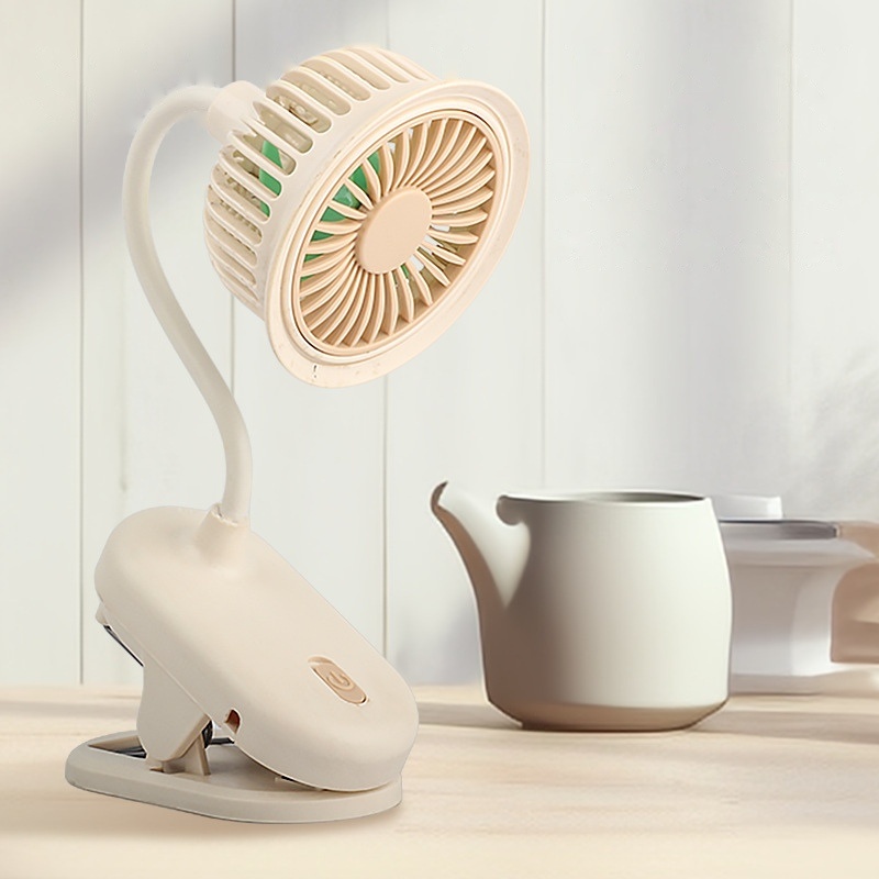 A cream clip fan beside a teapot on a sunlit wooden table
